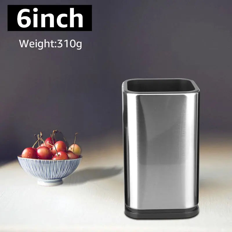 Stainless steel trash can next to a bowl of apples on a neutral background