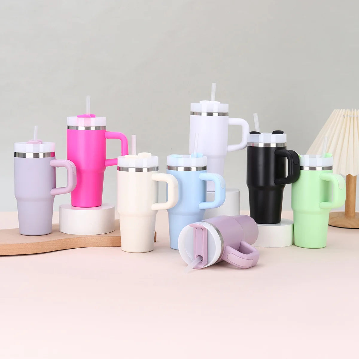 Assorted colorful tumblers with handles on a light surface.