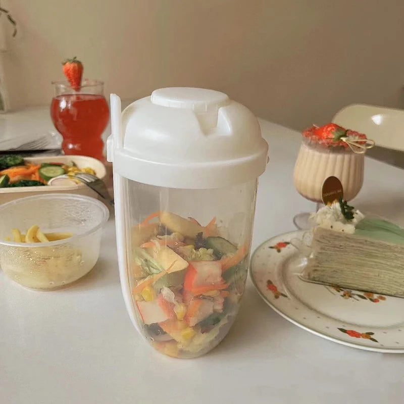 Container with salad on a table with food and drinks in the background