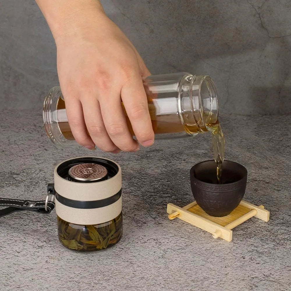 Hand pouring liquid from a glass container into a black cup on a gray surface.