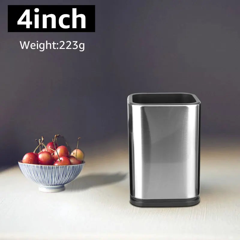 Small metallic trash bin next to a bowl of apples on a dark background