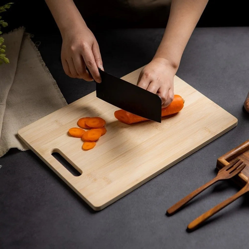 Person cutting carrots on a wooden cutting board with a knife.