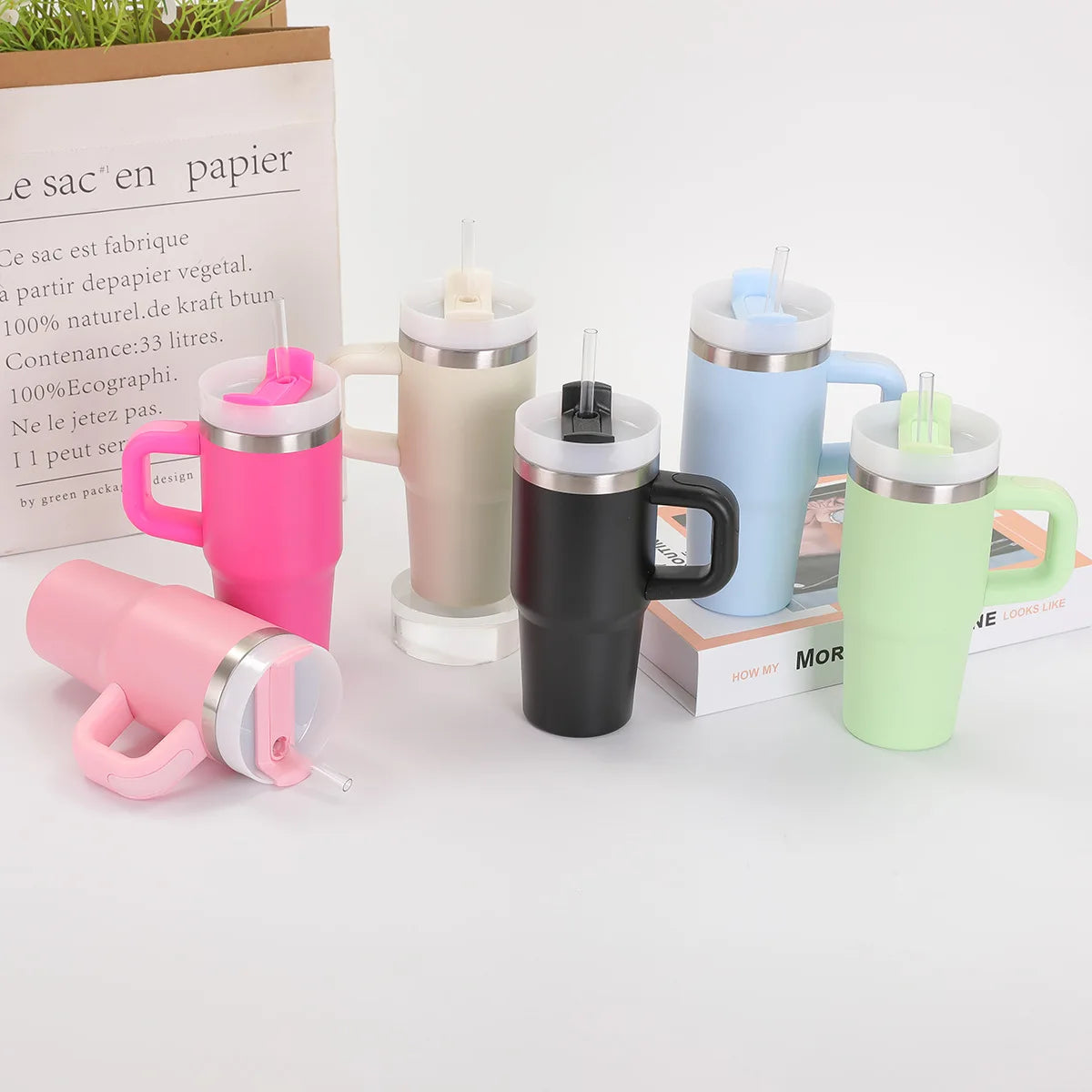 Colorful insulated mugs with handles and spout covers on a white surface.