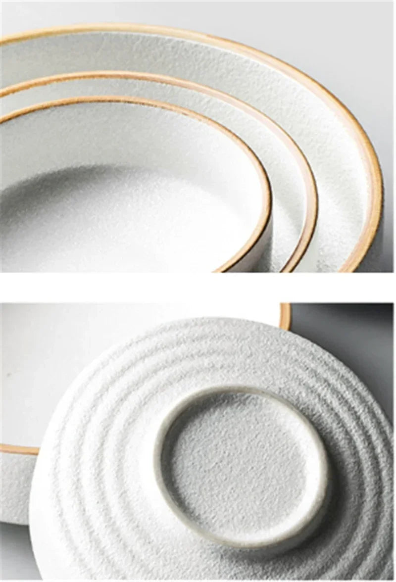 Set of white ceramic plates with gold rims on a light gray background