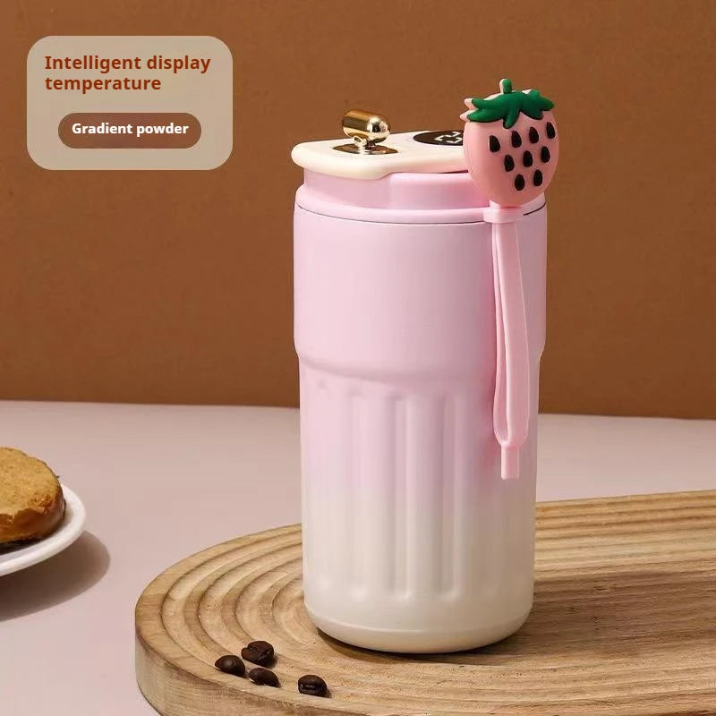 Pink thermos with strawberry design on a wooden surface