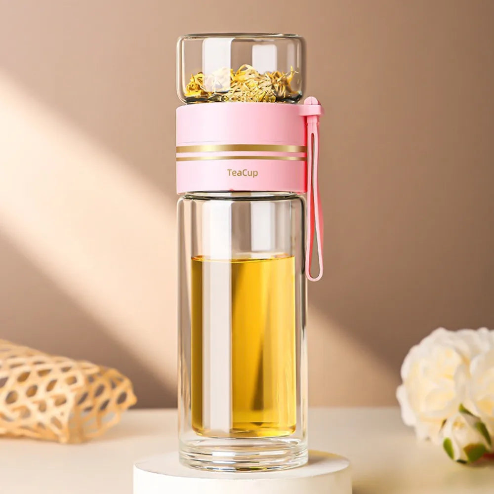 Glass tea cup with pink lid and handle filled with yellow liquid on a beige background
