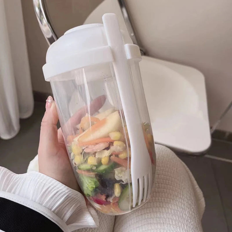 Clear container with colorful gummy bears and a white fork, held by a person.