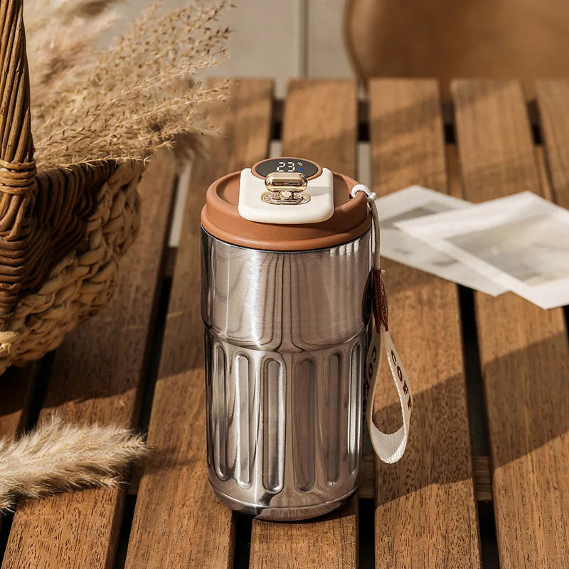 Stainless steel tumbler with brown lid on a wooden surface