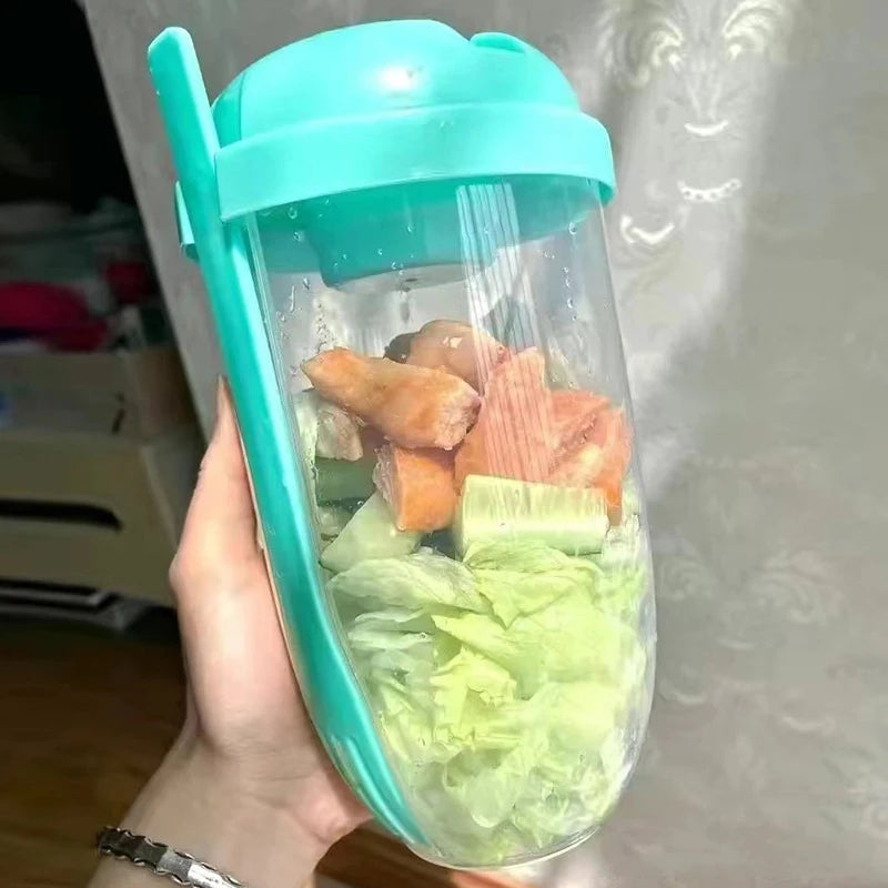 Hand holding a container with vegetables inside, likely for a smoothie or salad.