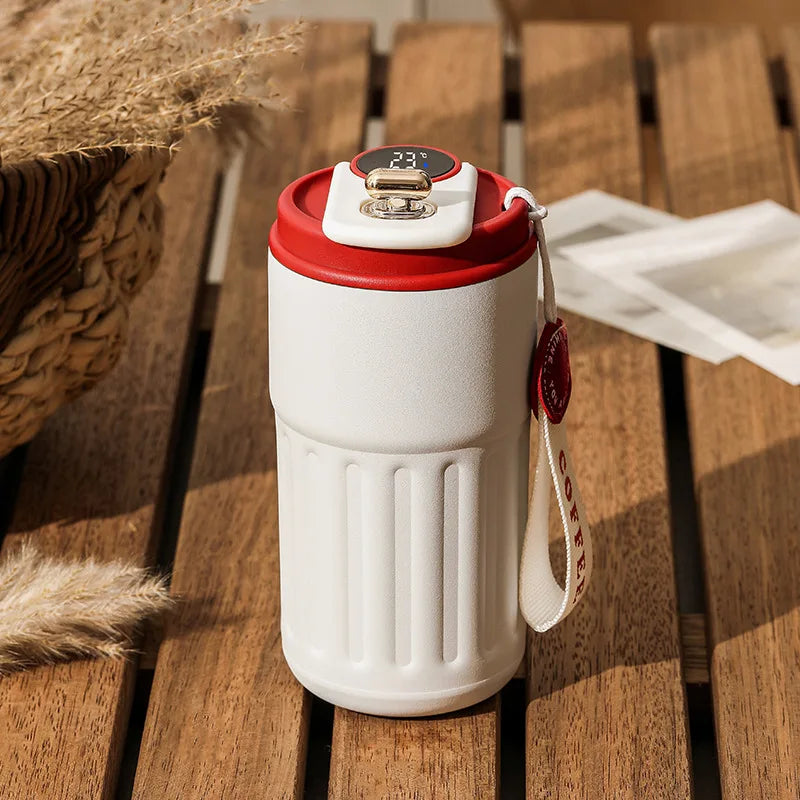 White travel mug with red lid on a wooden surface